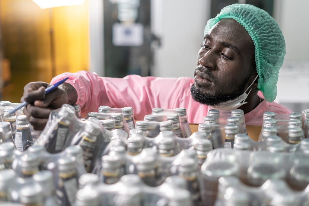 Food plant worker in a hairnet inspecting product for quality, tied to food and beverage recalls